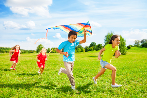 Group of kids run with kite